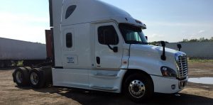 A white semi-truck parked on a gravel surface